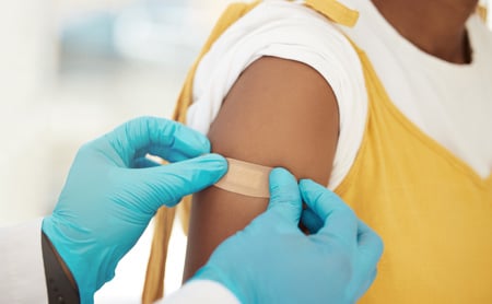 A doctor puts a bandage on a patient's arm after giving a vaccine