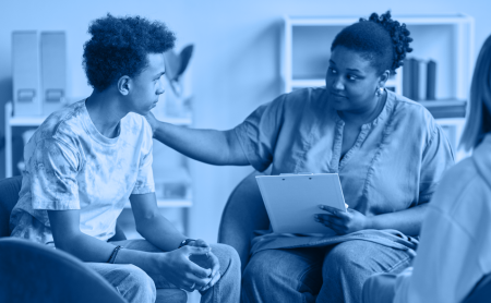 A counselor gives guidance to a young man, blue wash over the image