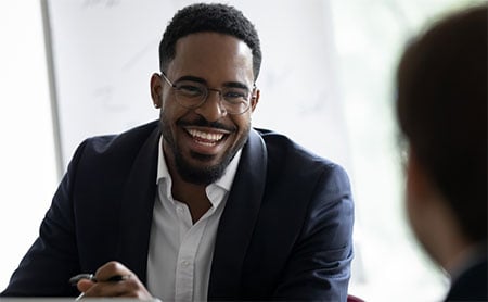 A man in a suit smiling during a conversation.
