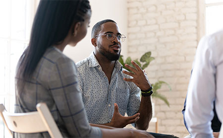 Three individuals engaged in a discussion in a casual office setting.