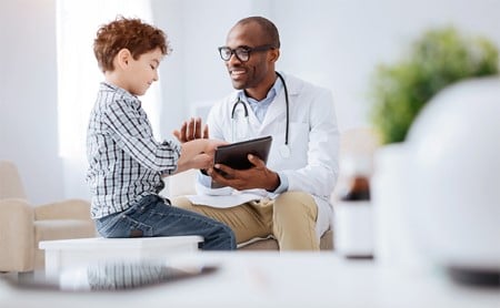 Smiling child using his doctor's tablet during an office visit