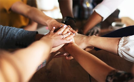 "Hands in" circle, symbolizing teamwork