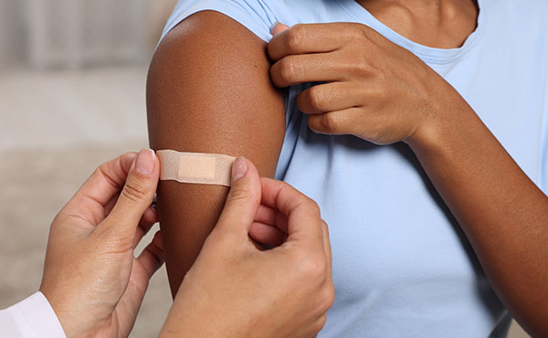 Doctor applying band-aid to person's arm after they received a vaccine