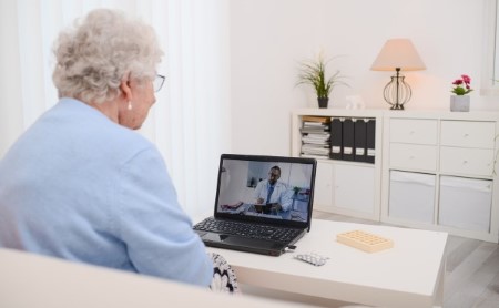Elderly woman in her home having a telehealth appointment with a doctor on a laptop