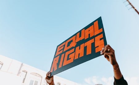 Black protest sign with EQUAL RIGHTS on it, letters are constructed of red tape