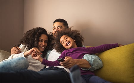 Mother, father and child laughing together on a couch