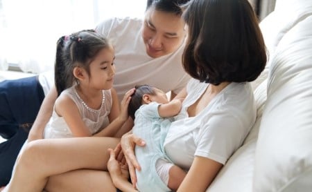 Family with young girl and breastfeeding newborn