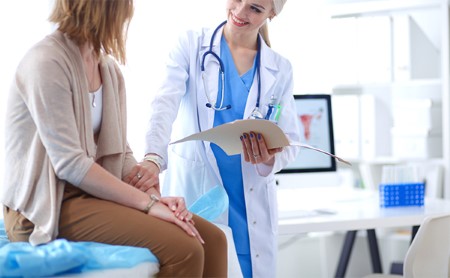 OBGYN lays a reassuring hand on her seated patient's arm during an office visit