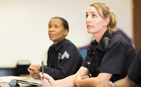 Two first responders in a classroom setting, taking notes