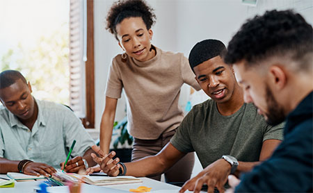 Four black colleagues having a discussion in an office.