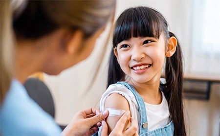 Smiling girl gets a bandage from a nurse after a vaccination shot