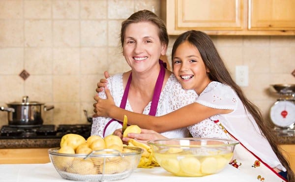 Girl hugging her grandmother while they prepare food