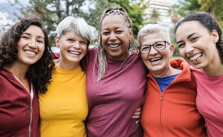 Group of women of different ages and races hugging each other and smiling