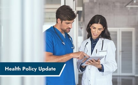 Two doctors in a hospital hallways conferring over a patient chart. ASTHO Health Policy Update banner in the lower left