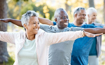 Healthy aging older adults with arms outstretched in a park setting