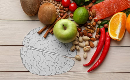 Fresh, healthy foods spilling across a picnic table, which has a greyscale illustration of a brain on it