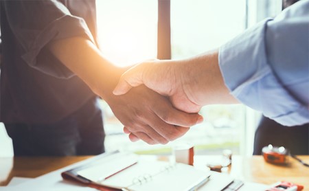 Midsection shot of two men shaking hands in an office