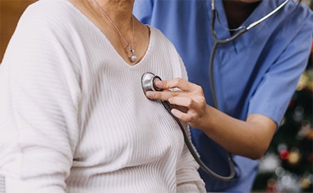 Mid-section of medical professional placing a stethoscope on a person's chest