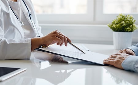 A doctor explains health information to their patient while sitting at a desk