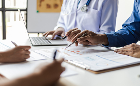 Midsection shot of doctors standing around a table, working on medical charts