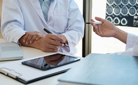 Midsection shot of two seated doctors discussing treatments