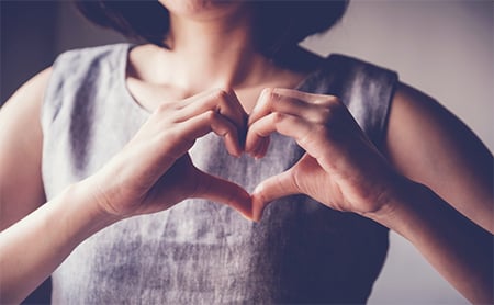 Misection photo of a woman making a heart symbol with her hands