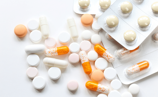 A variety of colorful pills and capsules scattered across a clean white surface.