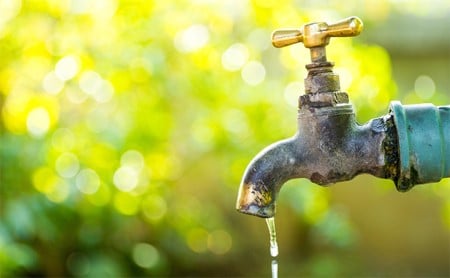  An outdoor spigot drips a steady stream of clear water