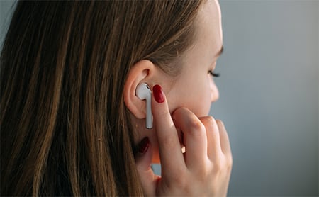 Over-the-shoulder view of a woman putting in earbuds
