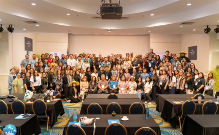 A large group of Population Health Summit attendees convene in a conference room.