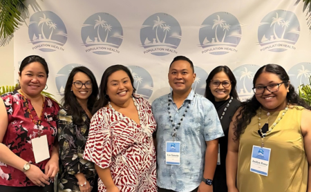 Population Health Summit Planning Committee members gather in front of a conference banner.