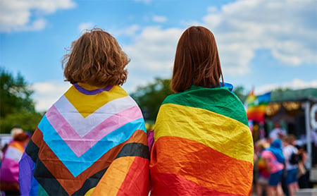 Two people wrapped in pride flags at a festival
