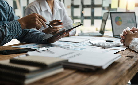 people-around-wood-table-full-of-reports-discussing-finance.jpg