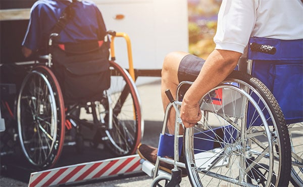 Disabled people on wheelchairs going onto a public bus