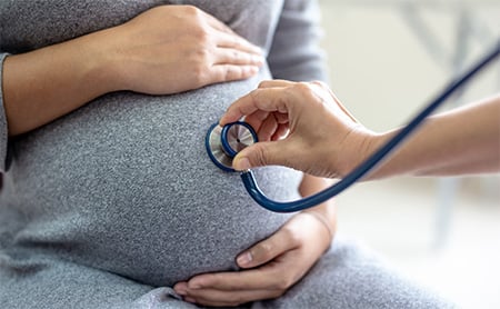 Midsection shot of a stethoscope on a pregnant person's belly