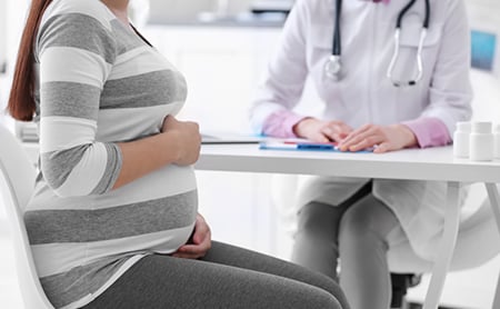 Midsection shot of a pregnant woman sitting across the desk from her doctor during an office visit