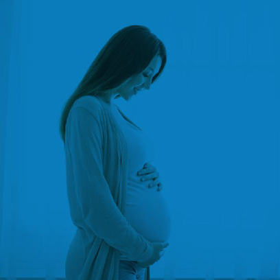 Pregnant white woman with long hair looking down at her belly with her hands placed on her belly in blue tones