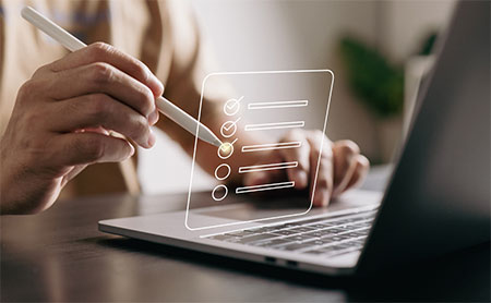 Person using a stylus to mark a checklist on a laptop screen.