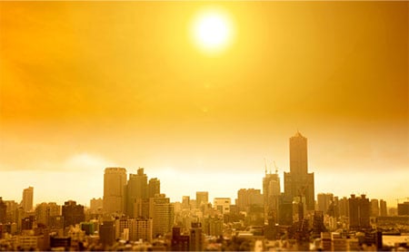 City skyline from a distance with sun, all in a yellow wash