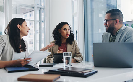 Three individuals engaged in a discussion in an office conference room.