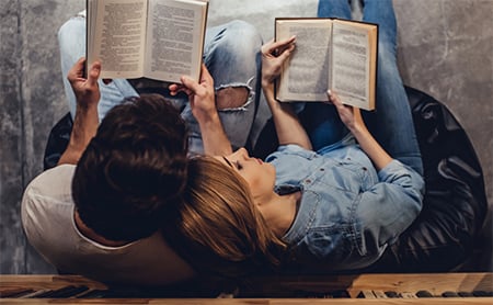 Overhead shot of man and woman, snggled together, reading books
