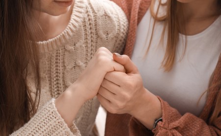Two female friends holding hands for emotional support
