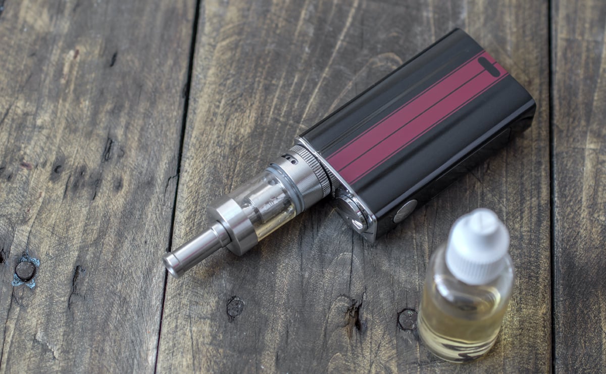 E-cigarette or vaping device and a bottle of e-liquid on wood table