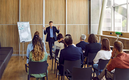 An individual is giving a presentation to a group of attentive listeners.