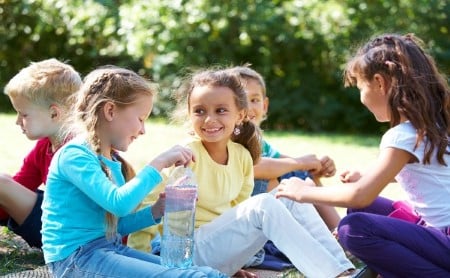 A group of young girls sitting outside drinking water