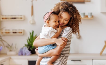 A young woman of color snuggles with her baby