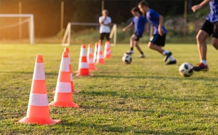 Three youth soccer players at afternoon practice participating in a dribbling drill