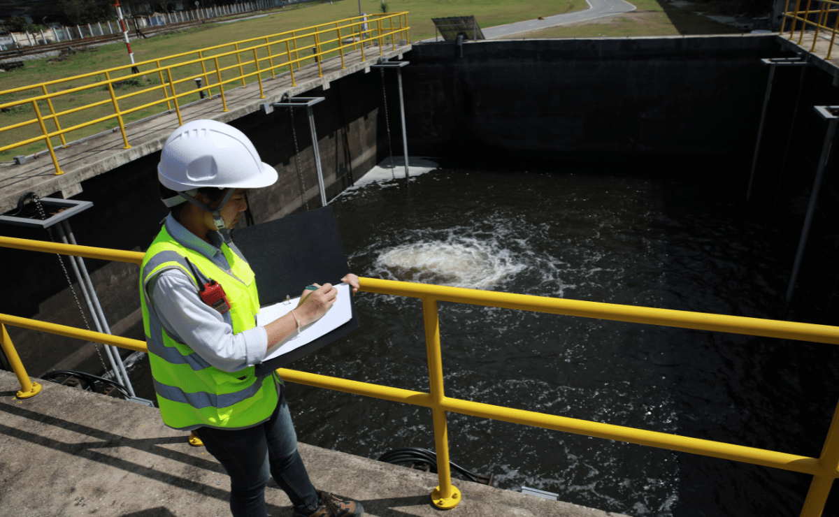 construction worker writing on clipboard next to water